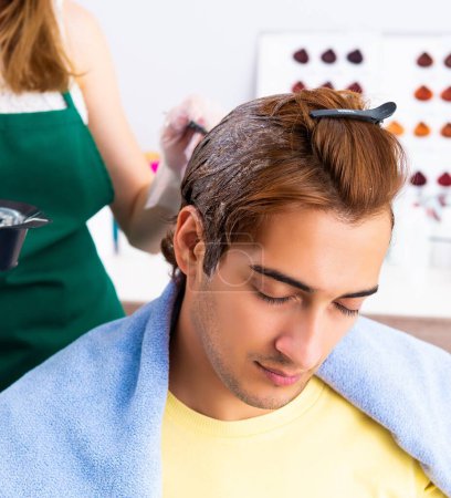Foto de La peluquera mujer aplicando tinte al cabello del hombre - Imagen libre de derechos