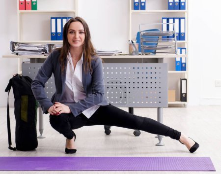 Téléchargez les photos : The female employee doing sport exercises in the office - en image libre de droit