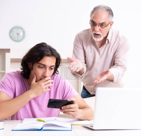 Téléchargez les photos : Le vieux père aidant son fils dans la préparation de l'examen - en image libre de droit