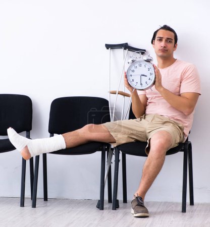 Photo for The young injured man waiting for his turn in hospital hall - Royalty Free Image