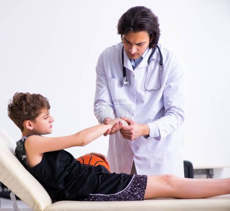 Foto de El jugador de baloncesto chico visitando al joven médico traumatólogo - Imagen libre de derechos