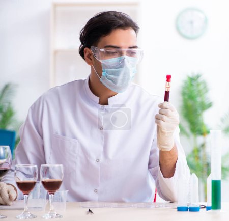 Photo for The male chemist examining wine samples at lab - Royalty Free Image