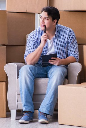Téléchargez les photos : Jeune homme emménageant dans une nouvelle maison avec des boîtes - en image libre de droit