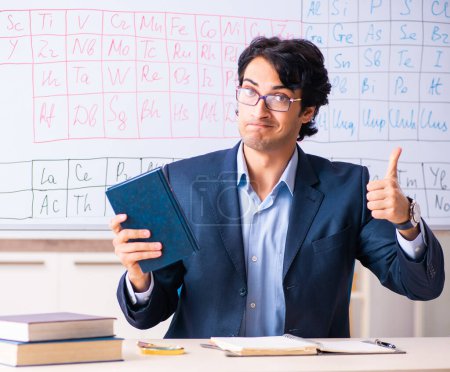 Téléchargez les photos : Le jeune professeur de chimie masculine devant le tableau périodique - en image libre de droit