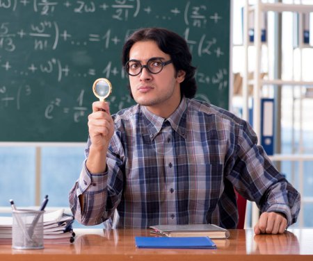 Téléchargez les photos : Le jeune professeur de mathématiques drôle en face du tableau - en image libre de droit