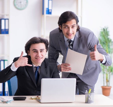 Foto de Los dos jóvenes empleados que trabajan en la oficina - Imagen libre de derechos