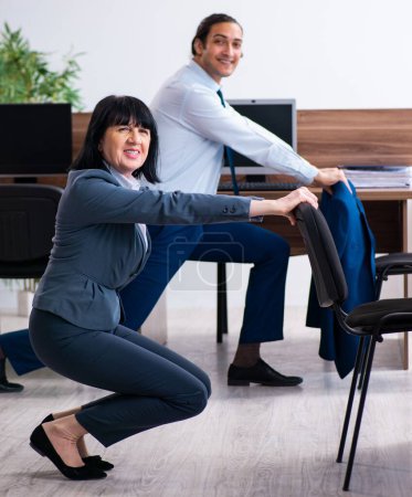 Téléchargez les photos : Les deux employés qui font des exercices sportifs au bureau - en image libre de droit
