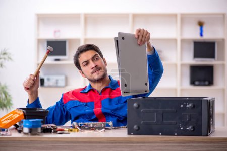Téléchargez les photos : Jeune réparateur réparer l'ordinateur à l'atelier - en image libre de droit