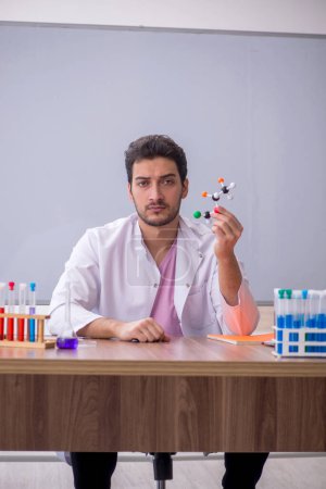 Téléchargez les photos : Young chemistry teacher sitting in the classroom - en image libre de droit