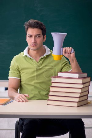 Foto de Young male student holding megaphone in classroom - Imagen libre de derechos