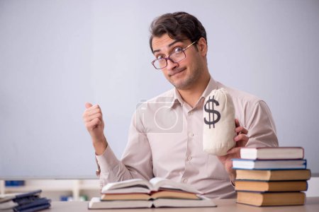 Photo for Young student holding moneybag in the classroom - Royalty Free Image