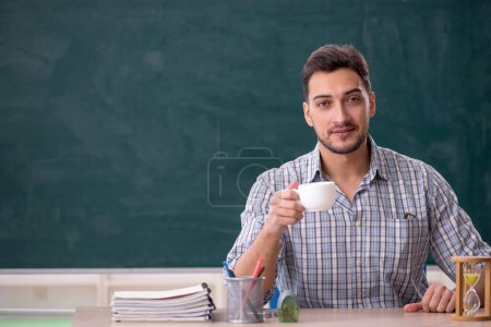 Téléchargez les photos : Young teacher drinking tea in the classroom - en image libre de droit