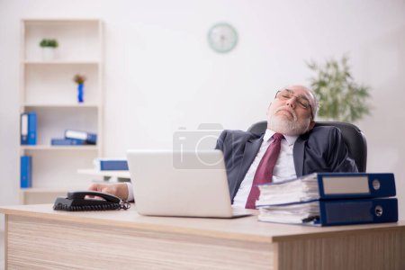 Foto de Viejo empleado de negocios y demasiado trabajo en el lugar de trabajo - Imagen libre de derechos
