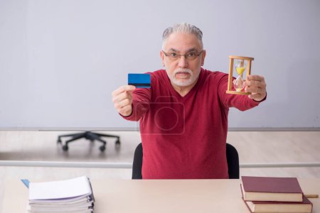 Foto de Antiguo profesor con tarjeta de crédito en la oficina - Imagen libre de derechos
