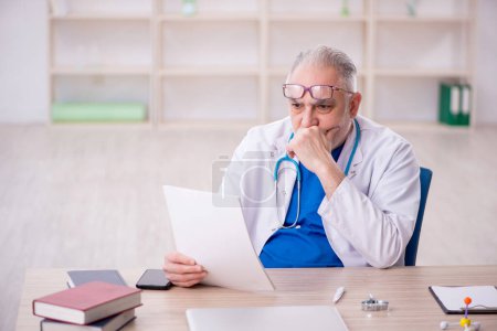 Téléchargez les photos : Old doctor sitting at the hospital - en image libre de droit