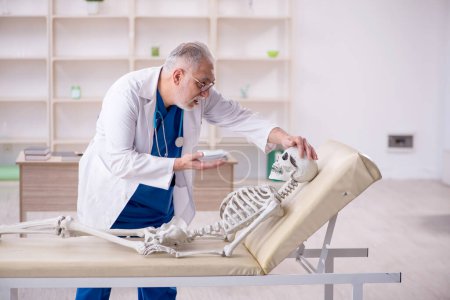 Téléchargez les photos : Old male doctor and skeleton patient at the hospital - en image libre de droit