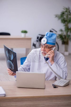 Téléchargez les photos : Old docror otolaryngologist working at the hospital - en image libre de droit