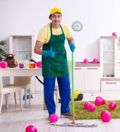 Téléchargez les photos : Le jeune entrepreneur masculin faisant des travaux ménagers après la fête - en image libre de droit