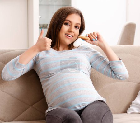 Foto de La joven embarazada sentada en el sofá en casa - Imagen libre de derechos