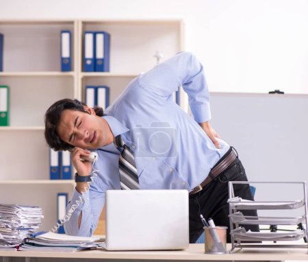 Téléchargez les photos : Le jeune bel employé masculin faisant des exercices dans le bureau - en image libre de droit