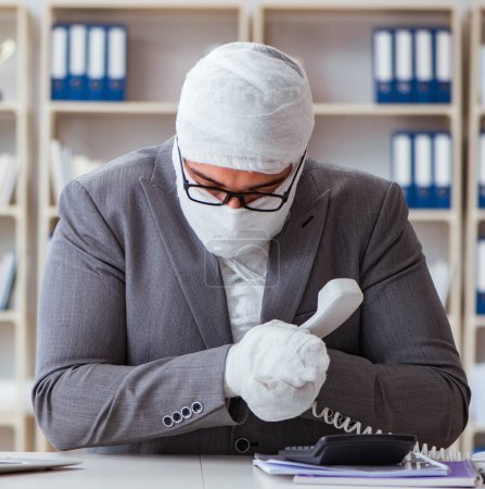 Téléchargez les photos : Homme d'affaires bandé travaillant dans le bureau faisant de la paperasserie - en image libre de droit
