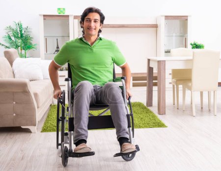 Téléchargez les photos : The young handsome man in wheelchair at home - en image libre de droit