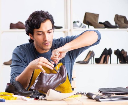 Photo for The young man repairing shoes in workshop - Royalty Free Image