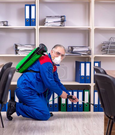Photo for The old professional contractor doing pest control in the office - Royalty Free Image