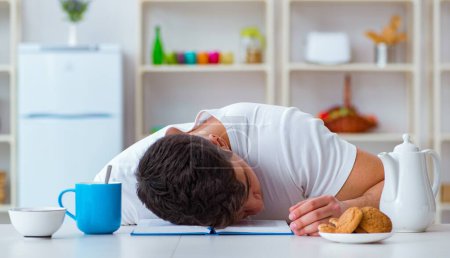 Téléchargez les photos : L'homme s'endort pendant son petit déjeuner après avoir fait des heures supplémentaires - en image libre de droit