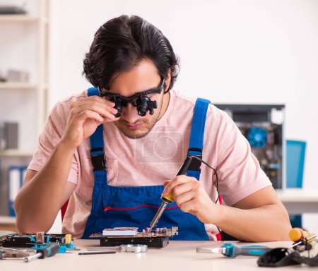 Téléchargez les photos : Le jeune entrepreneur masculin réparer l'ordinateur - en image libre de droit