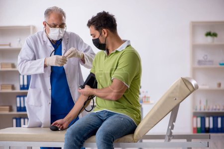 Téléchargez les photos : Vieux médecin mesurant la pression artérielle des jeunes patients - en image libre de droit