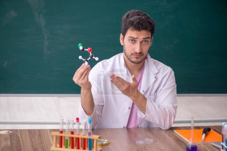 Téléchargez les photos : Young chemistry teacher sitting in the classroom - en image libre de droit