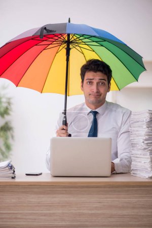 Téléchargez les photos : Young employee holding an umbrella at workplace - en image libre de droit