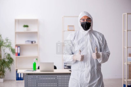 Foto de Joven contratista desinfectando oficina durante pandemia - Imagen libre de derechos