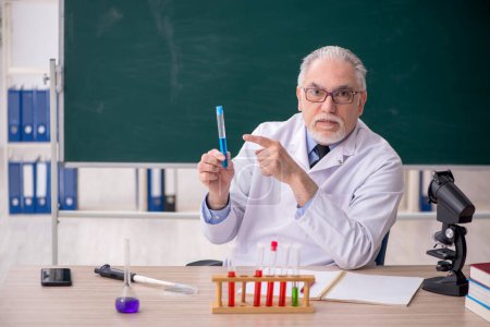 Téléchargez les photos : Old chemist teacher sitting in the classroom - en image libre de droit