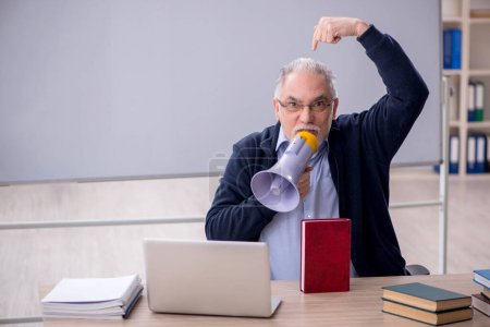 Téléchargez les photos : Old teacher holding megaphone in the classroom - en image libre de droit