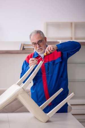 Téléchargez les photos : Old repairman repairing chair at home - en image libre de droit