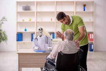 Foto de Viejo paciente masculino en silla de ruedas visitando esqueleto médico - Imagen libre de derechos