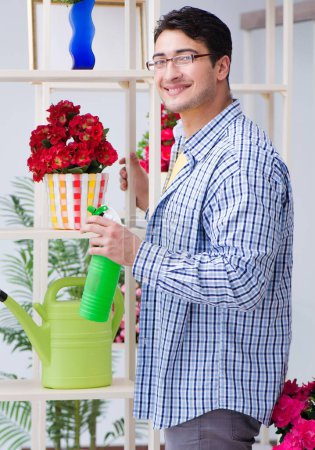 Téléchargez les photos : Le fleuriste jardinier travaillant dans un magasin de fleurs avec des plantes maison - en image libre de droit