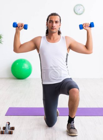 Photo for The young handsome man doing sport exercises indoors - Royalty Free Image