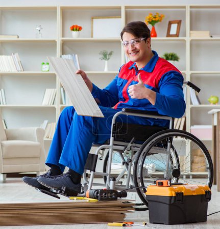 Foto de El hombre discapacitado que pone piso laminado en la oficina - Imagen libre de derechos