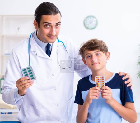 Téléchargez les photos : Le jeune homme médecin examinant garçon à la clinique - en image libre de droit