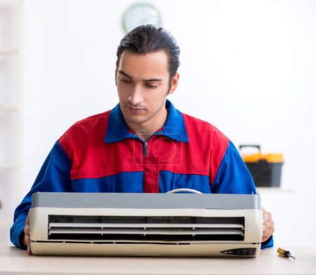 Photo for The young repairman repairing air-conditioner at warranty center - Royalty Free Image