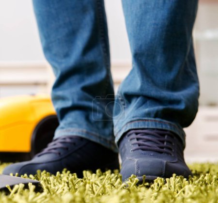 Foto de El hombre que limpia la alfombra del suelo con una aspiradora de cerca - Imagen libre de derechos