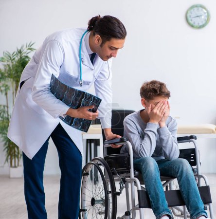 Photo for The young male doctor pediatrist and boy in wheel-chair - Royalty Free Image