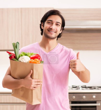 Photo for The young handsome man with vegetables in the kitchen - Royalty Free Image