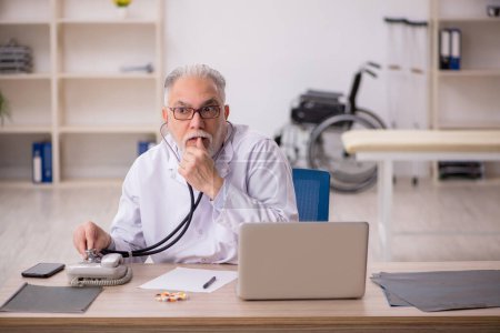 Téléchargez les photos : Vieux médecin travaillant à la clinique - en image libre de droit