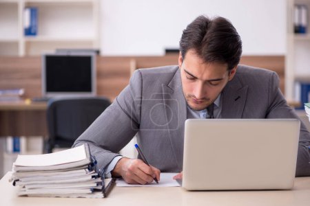 Photo for Young businessman employee unhappy with excessive work at workplace - Royalty Free Image