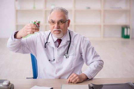 Foto de Viejo doctor sugiriendo pastillas en la clínica - Imagen libre de derechos