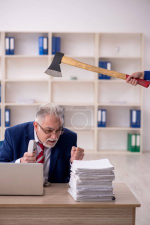 Foto de Old employee unhappy with excessive work at workplace - Imagen libre de derechos